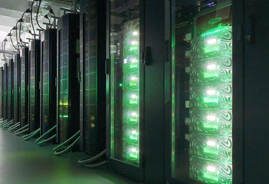 Picture of supercomputing racks with green light.